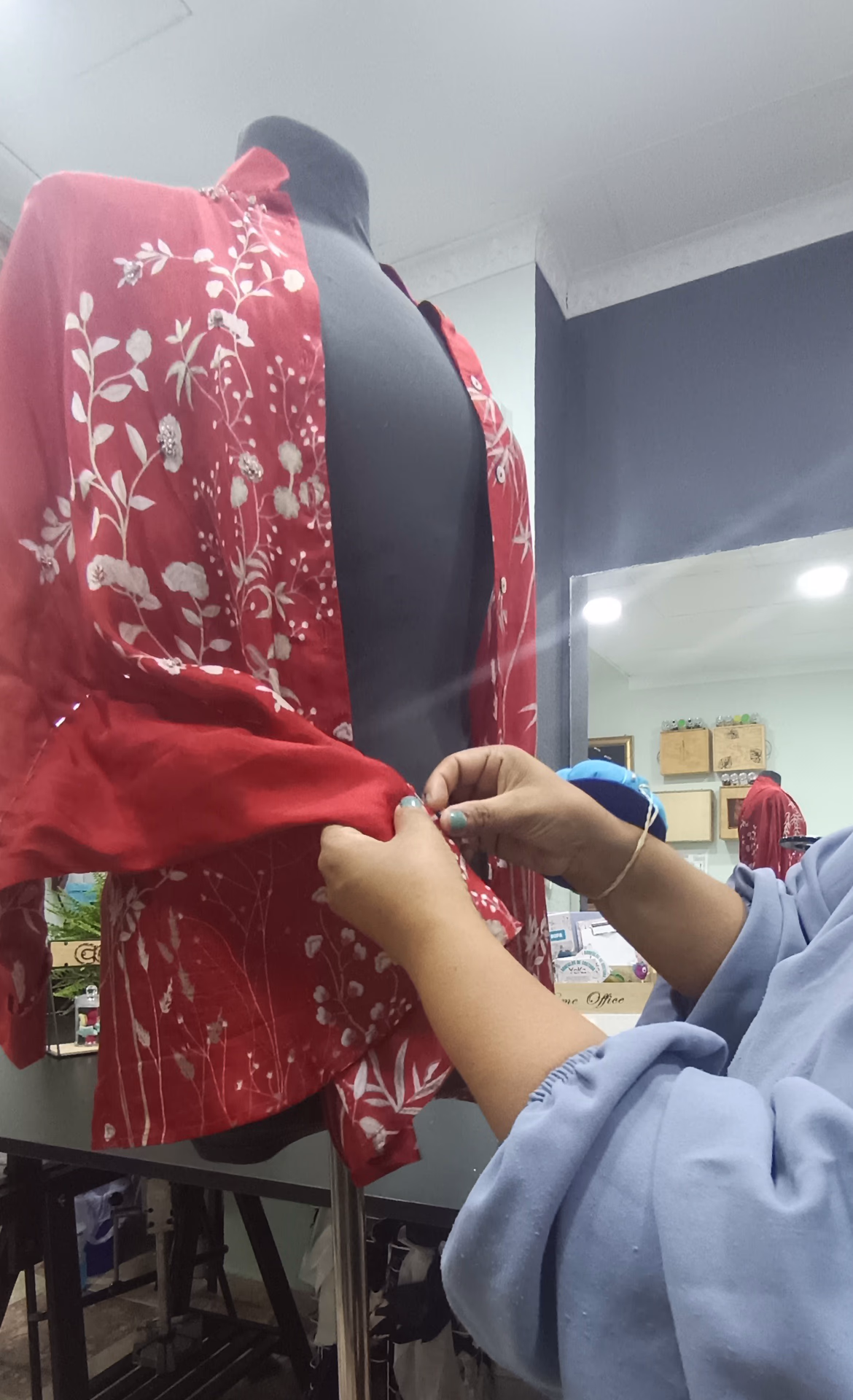 Maestra costurera YeKa realizando ajustes de alta costura sobre un maniquí con tejido rojo bordado en su taller de Málaga.